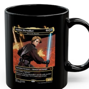 May include: Black ceramic mug featuring a Star Wars-themed graphic of Anakin Skywalker, a Human Jedi Knight, with a lightsaber. The mug has a curved handle and the text "Anakin Skywalker" is visible.