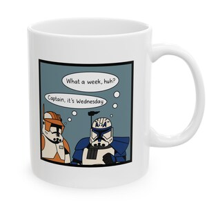 May include: White ceramic mug featuring a cartoon image of two Star Wars clone troopers. One trooper is orange and white, the other is blue and white. Speech bubbles read "What a week, huh?" and "Captain, it's Wednesday."