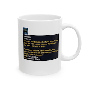 Könnte beinhalten: Weißer Keramikbecher mit einem schwarzen Rechteck mit Text über "Invincible", einem fliegenden untoten Pferd. Der Text enthält Spieldetails wie "1,5 Sek. Zauberzeit" und ein Zitat über die Stärke des Reittiers. Der Becher hat einen gebogenen Griff.