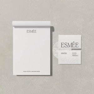 May include: A minimalist stationery set featuring a white notepad and business cards. The notepad has a rolled top and the word "ESMEE" printed at the top. The business cards also display the word "ESMEE". The text "VISUAL POETRY BY BRANDING HOUSE" is printed at the bottom of the notepad.