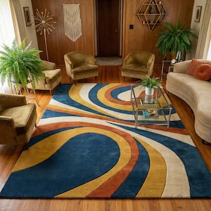 Colorful abstract area rug with curved geometric pattern in blue, mustard, rust, and cream tones placed in a modern mid century living room with wooden flooring and stylish furniture