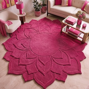 May include: A large, circular, deep pink area rug featuring a three-dimensional, layered petal design that radiates from a central circular core. The rug has a soft, textured surface with carved edges that define each individual petal shape.