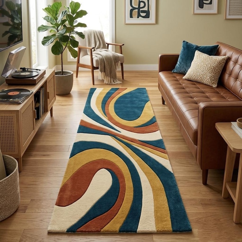 May include: A rectangular area rug with a retro design. The rug features a pattern of swirling lines in shades of blue, cream, mustard yellow, and rust. The rug is placed on a hardwood floor in a living room setting.