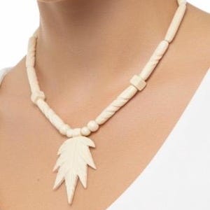 May include: A cream-colored necklace featuring a central leaf-shaped pendant suspended from a strand of alternating cylindrical, twisted, and square-shaped beads. The entire piece is monochromatic, showcasing a smooth, uniform finish throughout the design.