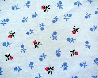 May include: A light blue fabric with a repeating pattern of small blue flowers and red flowers with black stems.