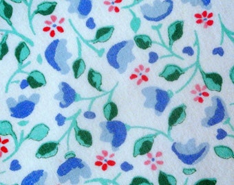 vintage des années 1970 matelassant le tissu de couture en coton inutilisé de haute qualité avec des fleurs roses/bleues imprimées et des feuilles vertes sur la couleur de fond blanche