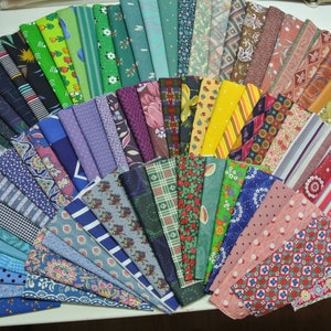 May include: A collection of fabric swatches in a variety of colors and patterns, arranged in a fan shape. The fabrics include floral prints, geometric patterns, stripes, and solids.
