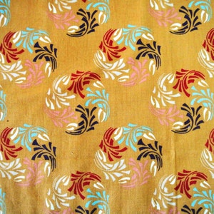 May include: A yellow fabric with a repeating pattern of stylized floral designs in white, red, blue, and pink.