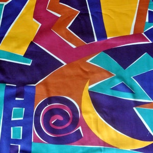 May include: Abstract geometric pattern fabric in shades of blue, yellow, orange, red, and green. The fabric features a variety of shapes, including circles, triangles, and squares.