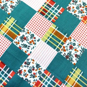 Peut inclure: Gros plan sur une courtepointe en patchwork avec un motif répétitif. La courtepointe présente des carrés sarcelle, rouges, blancs et jaunes avec des motifs floraux, à carreaux et vichy. La courtepointe a une esthétique vintage et faite à la main.