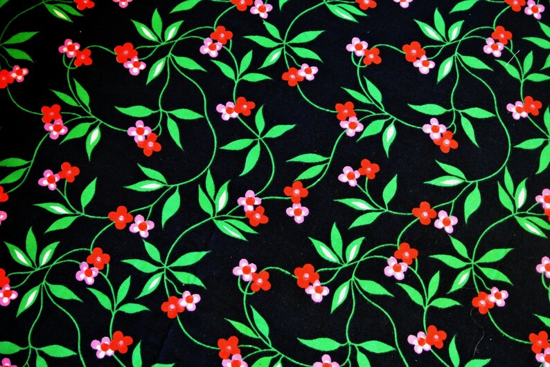 Op de afbeelding: Een zwarte stof met een herhalend patroon van roze en rode bloemen op groene ranken.