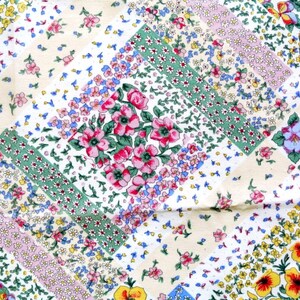 May include: A floral patchwork fabric with a cream background. The design features squares and diagonal stripes filled with various flowers in pink, yellow, blue, and green. The overall pattern is a mix of small and large floral arrangements.