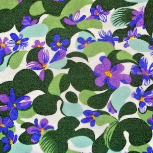 Peut inclure: Un tissu blanc avec un motif répétitif de fleurs violettes et bleues sur un fond de feuilles vertes.