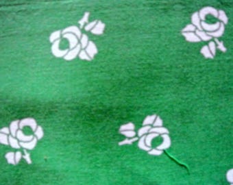 May include: Green fabric with a white floral pattern. The fabric features a repeating design of white roses with leaves.