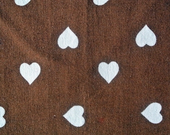 May include: A brown fabric background with a repeating pattern of white hearts.