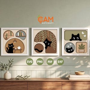 May include: Three square framed wall art pieces featuring layered paper-cut style illustrations of black cats. The designs include a cat with a teapot, a cat peeking from behind foliage, and a cat near a potted plant with white butterflies.