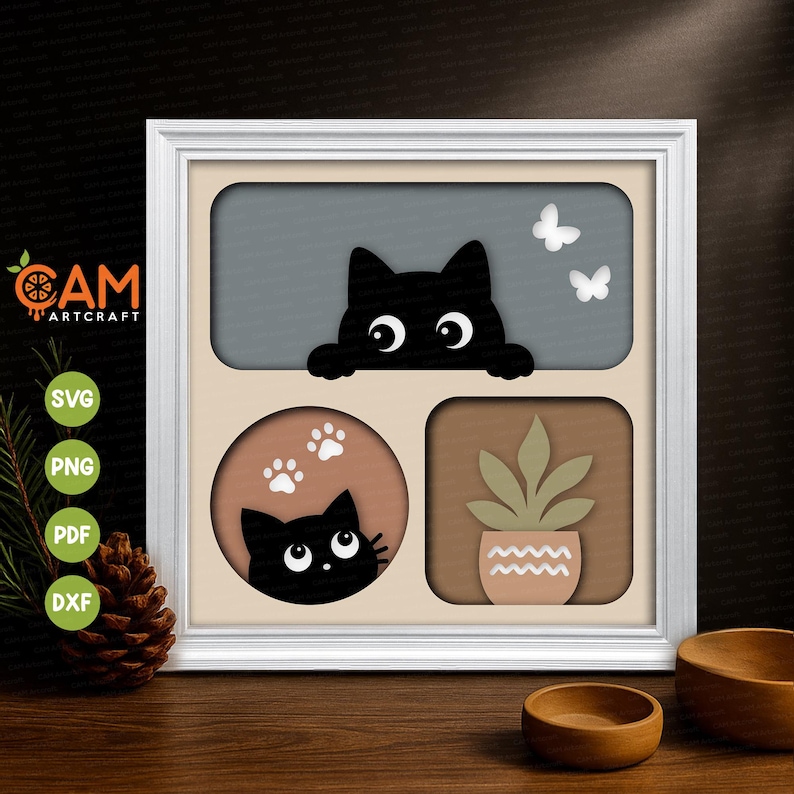 May include: A white framed multi-layered paper art piece featuring a black cat peeking over a gray rectangular cutout with two white butterflies, a circular cutout with a black cat and white paw prints, and a square cutout with a potted plant.