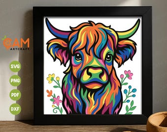 May include: A colorful framed print of a Highland cow with a vibrant, rainbow-colored coat. The artwork features a stylized design with a black frame, set against a white background with floral accents. The print is displayed on a wooden surface.