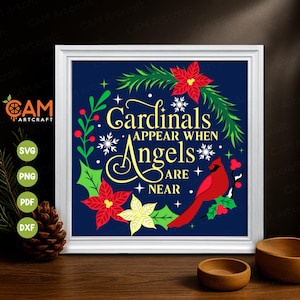May include: A framed print with the text "Cardinals Appear When Angels Are Near" surrounded by a wreath of red poinsettias, green leaves, and a red cardinal on a dark blue background. The frame is white.