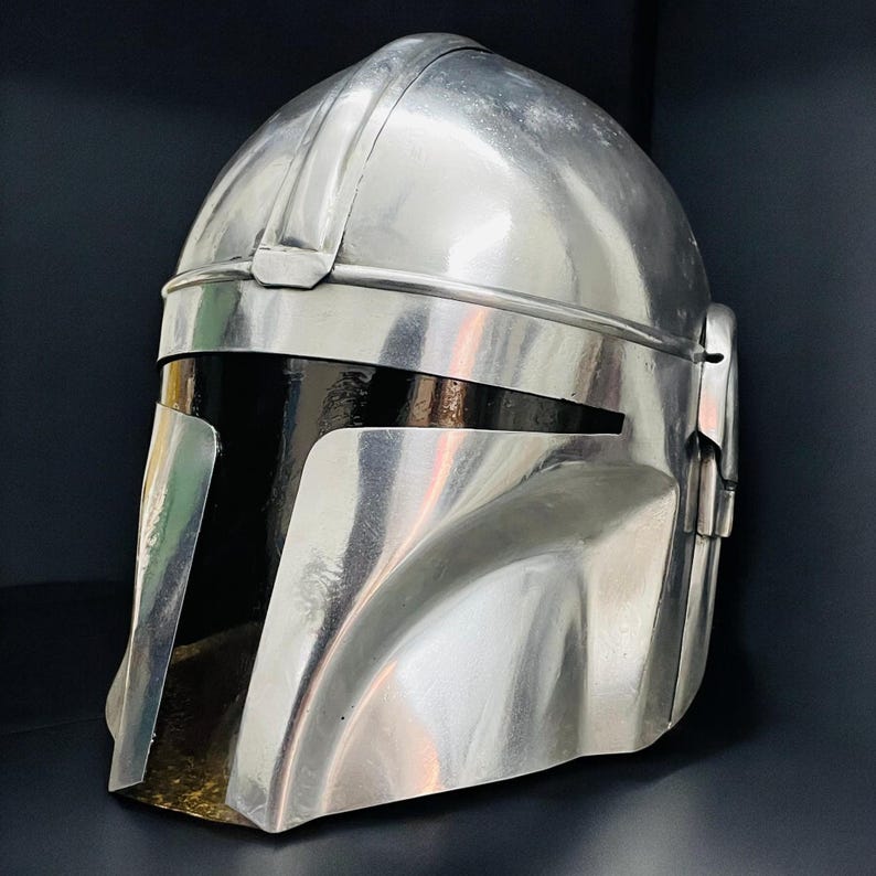 May include: A metallic silver helmet with a distinctive visor and a rounded top. The helmet has a sleek, futuristic design, with a dark interior visible through the visor opening. The overall aesthetic suggests a sci-fi or cosplay theme.