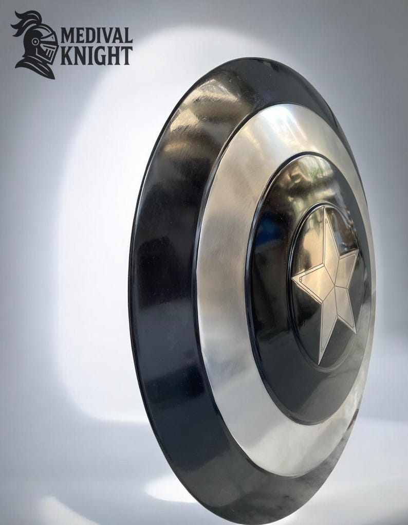 May include: A round shield with a black outer ring, a silver band, and a central black circle with a silver star. The shield has a glossy finish. The text "MEDIVAL KNIGHT" and a knight's helmet logo are in the upper left corner.