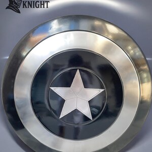 May include: A silver and black shield with a large, five-pointed star in the center. The shield has a circular design with a silver border and the text "MEDIVAL KNIGHT" in the upper left corner.