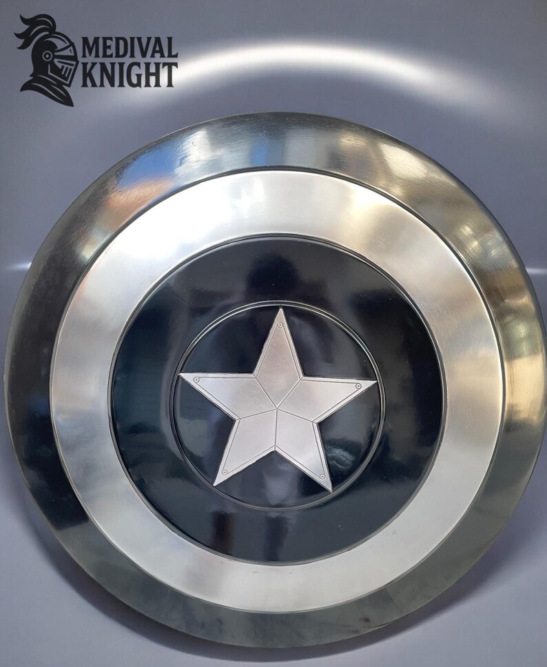 May include: A silver and black shield with a large, five-pointed star in the center. The shield has a circular design with a silver border and the text "MEDIVAL KNIGHT" in the upper left corner.
