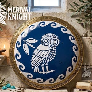 May include: A round shield with a blue center featuring a white owl design and olive branch. The shield has a gold border with a repeating pattern and is labeled "MEDIVAL KNIGHT" in white text. The shield is a decorative item.