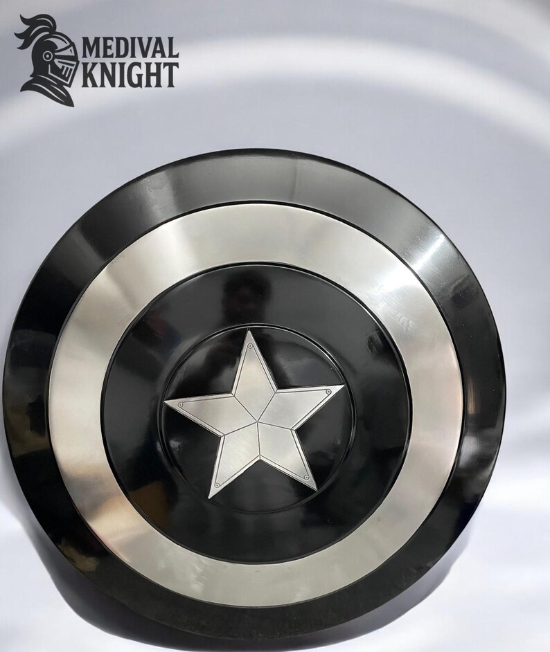 May include: A black and silver shield with a central silver star design. The shield has a circular shape with a black center, a silver ring, and a black outer rim. The text "MEDIVAL KNIGHT" is in the upper left corner.