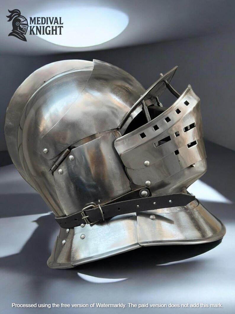 May include: A polished steel medieval knight's helmet with a visor and a leather strap. The helmet has a rounded top and a hinged visor with small rectangular openings. The text "MEDIVAL KNIGHT" is visible in the upper left corner.