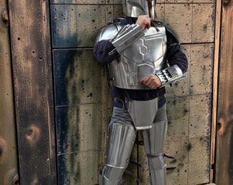 May include: A person in full silver armour, including a helmet, chest plate, and leg guards. The armour has a metallic sheen and is worn over a dark shirt and trousers. The image includes the text "MEDIVAL KNIGHT".