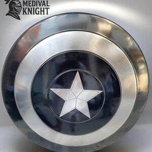 May include: A round, metallic shield with a central black circle featuring a silver five-pointed star. The shield has concentric silver and black rings, with the text "MEDIVAL KNIGHT" and a knight's helmet logo in the upper left corner.