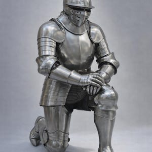 May include: A full suit of medieval armor in a kneeling position. The polished steel armor includes a helmet, chest plate, arm and leg protection, and gloves. The armor is highly detailed and reflects the light, creating a metallic sheen.