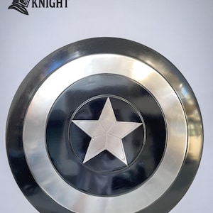 May include: A round, black and silver shield with a large, silver star in the center. The shield has a silver ring around the center star and a silver border. The text "MEDIVAL KNIGHT" is in the upper left corner.