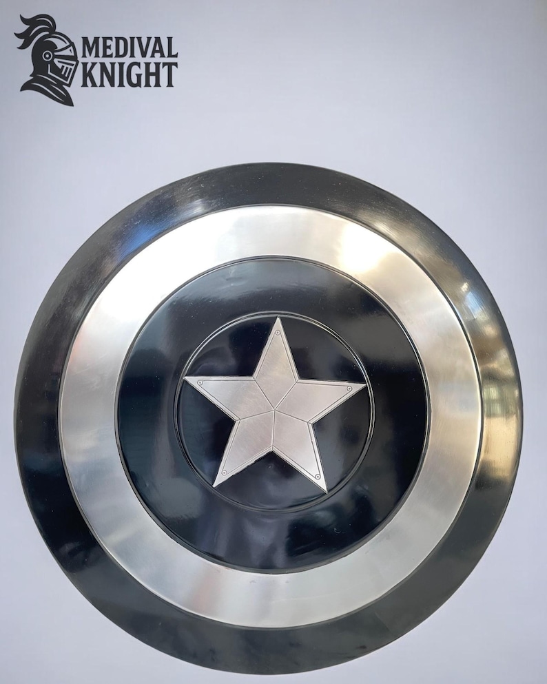 May include: A round, black and silver shield with a large, silver star in the center. The shield has a silver ring around the center star and a silver border. The text "MEDIVAL KNIGHT" is in the upper left corner.