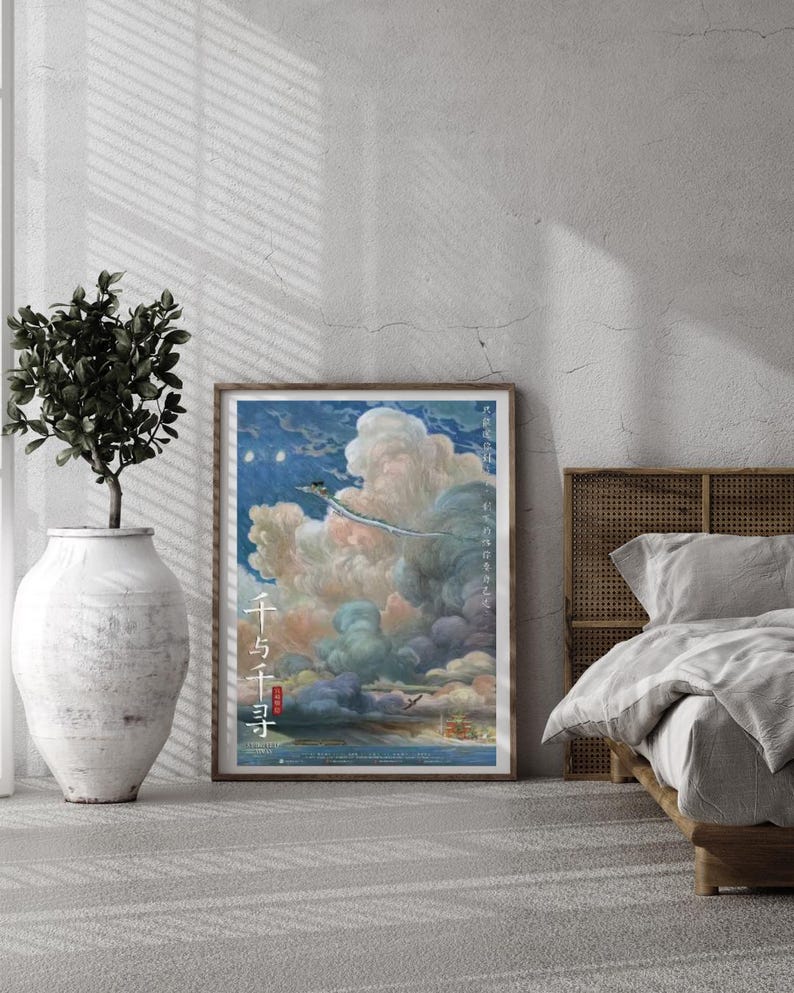 May include: A framed poster featuring a vibrant illustration of a fantastical scene with a flying creature soaring through clouds. The poster has Japanese text and is displayed in a bedroom setting with a plant in a large white vase.