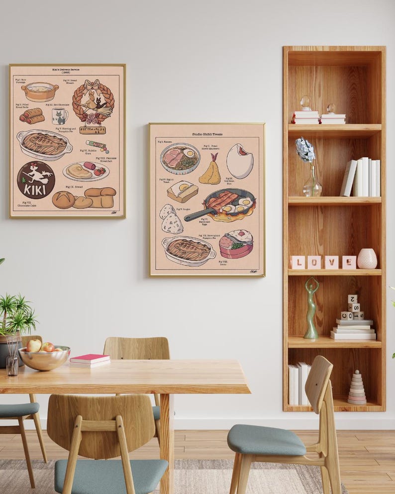 May include: Two framed art prints featuring illustrated food items. One print includes the text "Kiki's Delicious Dinner" and the other "Studio Kiki's Treats". The prints are displayed in a dining room setting with a wooden table and chairs.