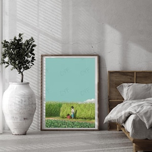 May include: A framed art print depicts two children in a field of green plants under a light blue sky. The artwork is displayed in a room with a large white vase holding a plant, and a bed with a woven headboard.