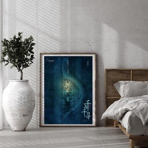 May include: A framed poster with a blue and teal abstract design, featuring Chinese characters. The poster is displayed on a light gray wall, next to a large white vase with a green plant. A bed with a wooden headboard is visible.