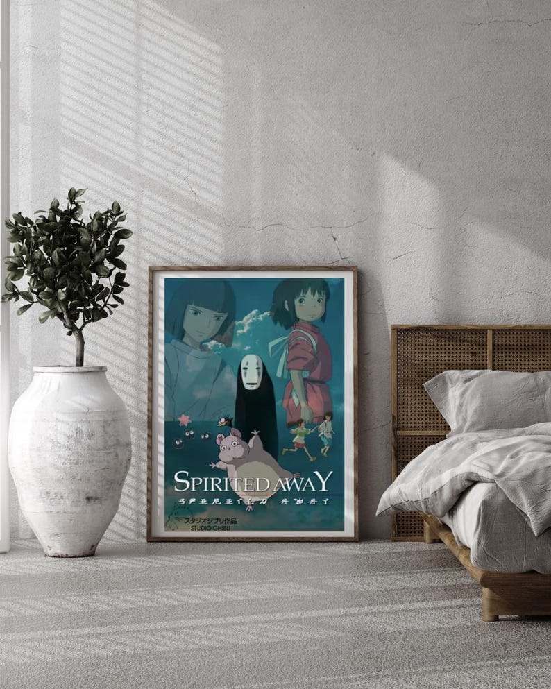 May include: A framed poster featuring artwork from the animated film "Spirited Away." The poster has a wooden frame and is displayed in a room with a neutral color scheme. The artwork depicts characters from the film in a vibrant, colorful style.