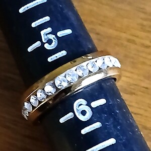 Clear Rhinestone Costume Ring US Sz 5.5 Statement Engagement Cocktail from Yours, Occasionally. Sparkly and simple, this ring is a US size 5 1/2 ladies ring. Whether you use it as an engagement or friendship ring it makes a lovely statement. The gold tone setting has bezel set clear rhinestones all the way around it. The ring is in excellent vintage* condition.