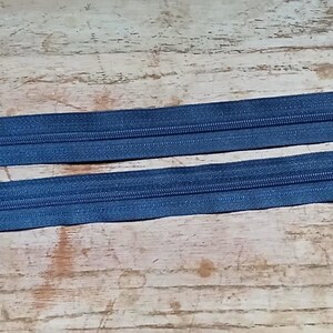 May include: Two blue denim zippers with silver metal pulls and the brand name "Ziplon" printed on the packaging. One zipper is 12 inches long, and the other is 17 inches long. The zippers are laid out on a wooden surface.