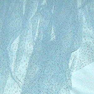 May include: Light blue tulle fabric with scattered silver glitter. The sheer material is draped and folded, creating a textured effect. The fabric is suitable for crafting, apparel, or decorative purposes.