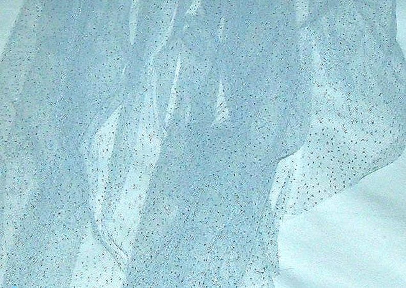 May include: Light blue tulle fabric with scattered silver glitter. The sheer material is draped and folded, creating a textured effect. The fabric is suitable for crafting, apparel, or decorative purposes.