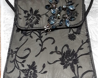 Bolso negro con estampado floral de Liz Claiborne con broche de pedrería azul.