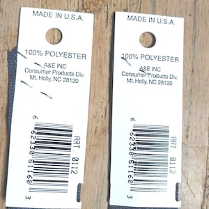 May include: Two dark gray zippers with white tags. The tags read "MADE IN U.S.A." and include the text "100% POLYESTER" and the manufacturer's information. Each tag has a barcode and the text "ART. 0112".