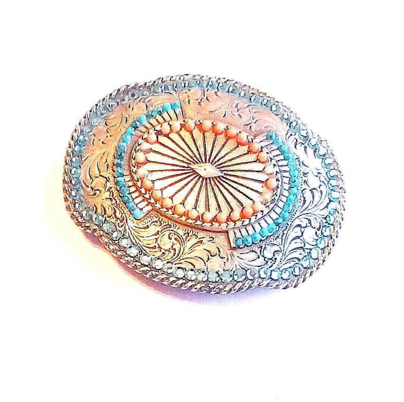 Ornate Belt Buckle Silver Tone Sunburst Design Rhinestones and Beads: Vintage Western Wear from Yours, Occasionally. Marvelous Floral and Sunburst designed buckle features turquoise colored rhinestones around outer edge with turquoise and coral beads in center. It is 3 3/4" long and 3" wide. The vintage* buckle is in excellent vintage* condition. It has been repaired as 4 beads in center were missing. See pictures 4 and 5.