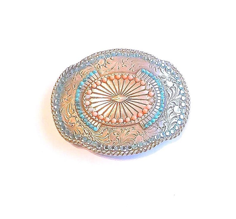 Ornate Belt Buckle Silver Tone Sunburst Design Rhinestones and Beads: Vintage Western Wear from Yours, Occasionally. Marvelous Floral and Sunburst designed buckle features turquoise colored rhinestones around outer edge with turquoise and coral beads in center. It is 3 3/4" long and 3" wide. The vintage* buckle is in excellent vintage* condition. It has been repaired as 4 beads in center were missing. See pictures 4 and 5.