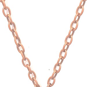May include: Close-up of a copper-coloured chain necklace. The chain is made of oval links and is set against a white background. The necklace is a simple, elegant design.