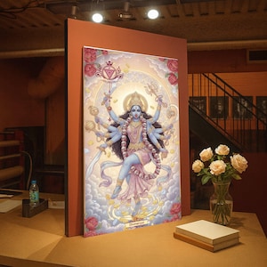 Puede incluir: Una obra de arte enmarcada que representa una deidad de múltiples brazos con piel azul, adornada con joyas y una guirnalda de calaveras. La obra presenta una paleta de colores claros con acentos florales y el texto "Divineryul" en la parte inferior.